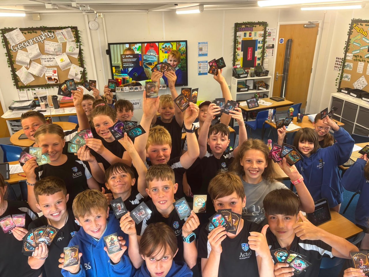 Primary school children in a classroom holding up Trivela FC player cards